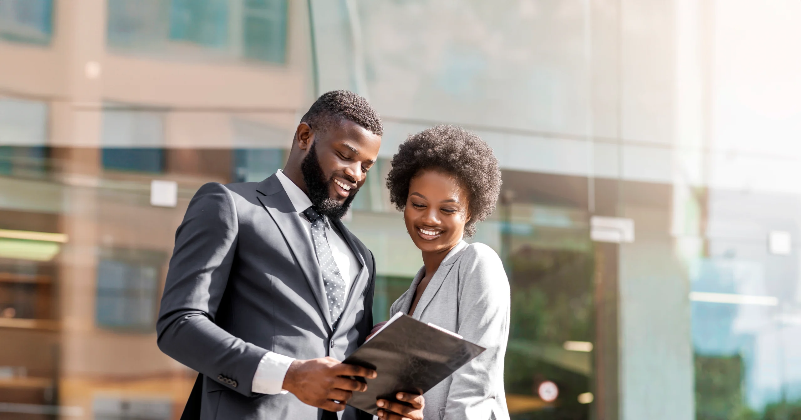 couple-african-business-partners-reading-finance-reports-outdoors-happy-about-monthly-results